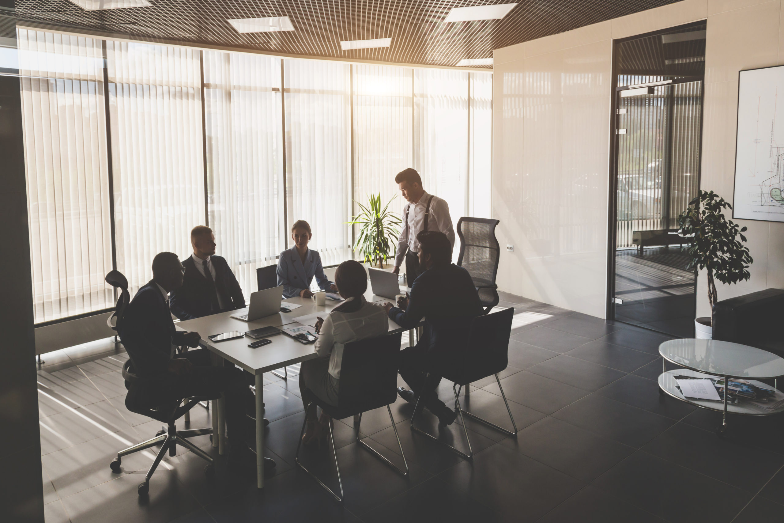 An office meeting taking place showing people sitting at a desk in discussion | Chambers and Partners